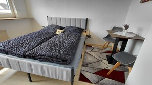 A modern bedroom with a bed, bedside table, and a small desk with a chair. - Apartment Naturoase Fichtelberg Kira & Suki with Mountain View and Wi-Fi (Fichtelberg)