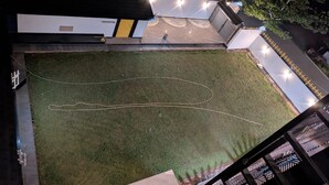 An aerial view of a building with a grassy courtyard, a pathway, and a person standing near the entrance. - Abhimaan (Mysore)
