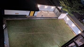An aerial view of a building with a grassy courtyard, a pathway, and a person standing near the entrance.