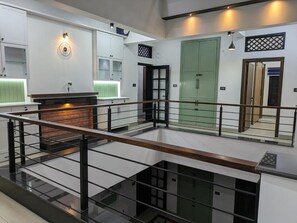A multi-level interior with a central staircase, a fireplace, and a green door.