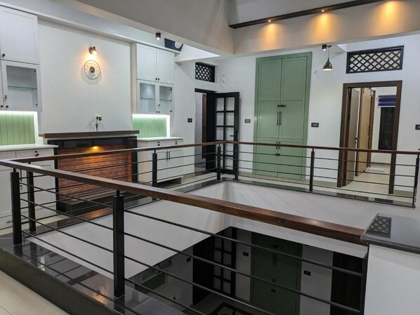 A multi-level interior with a central staircase, a fireplace, and a green door.