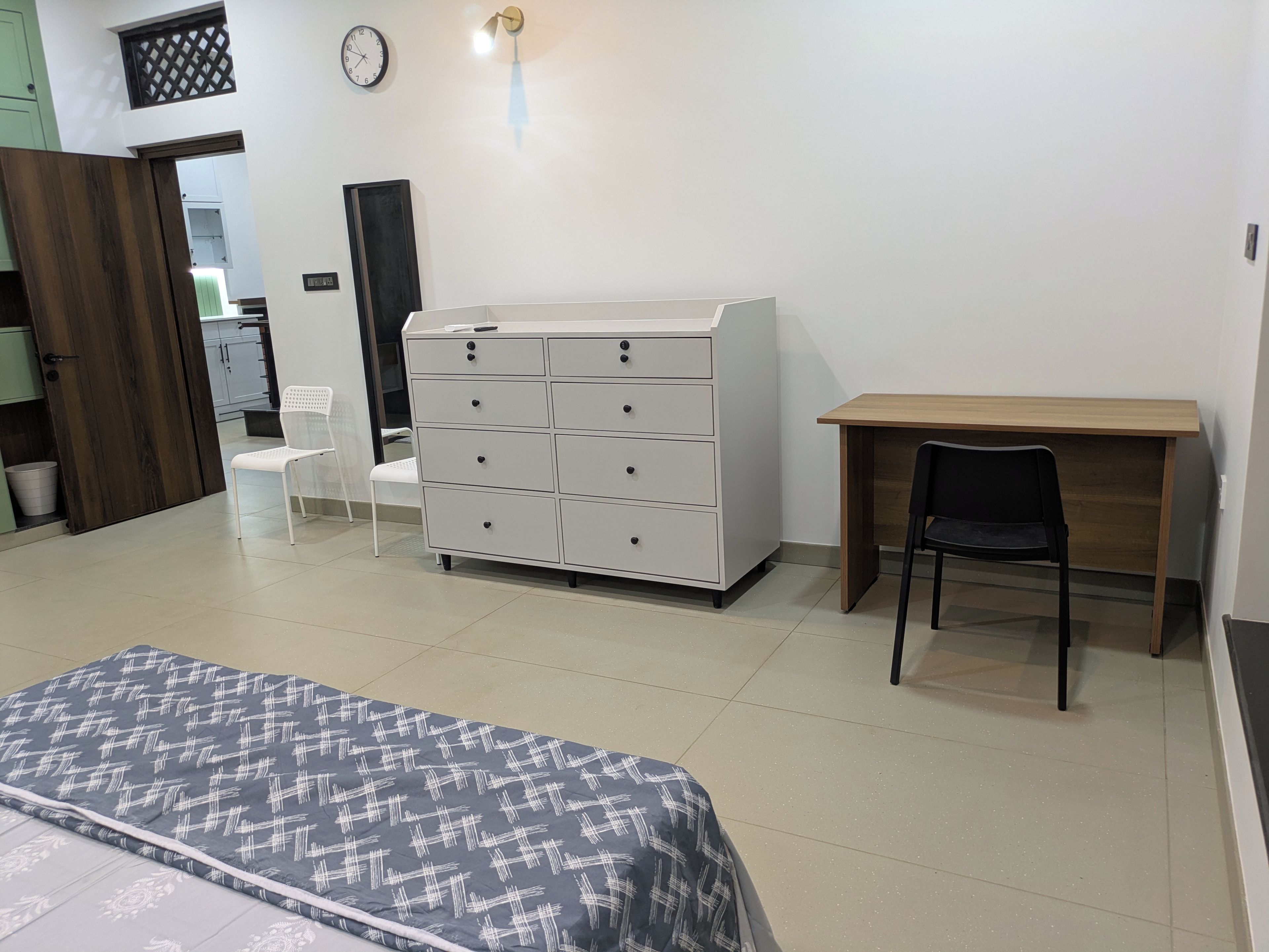 Un dormitorio con una cama, un aparador, un escritorio y una silla.