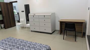 Un dormitorio con una cama, un aparador, un escritorio y una silla.