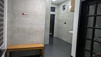 A hallway with a bench, a patterned wall, a door, and a rug.