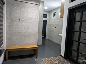 Un passadís amb una banca, un mur amb dibuixos, una porta i una catifes.