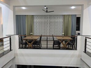 Un comedor con una mesa, sillas, ventilador de techo y cortinas.