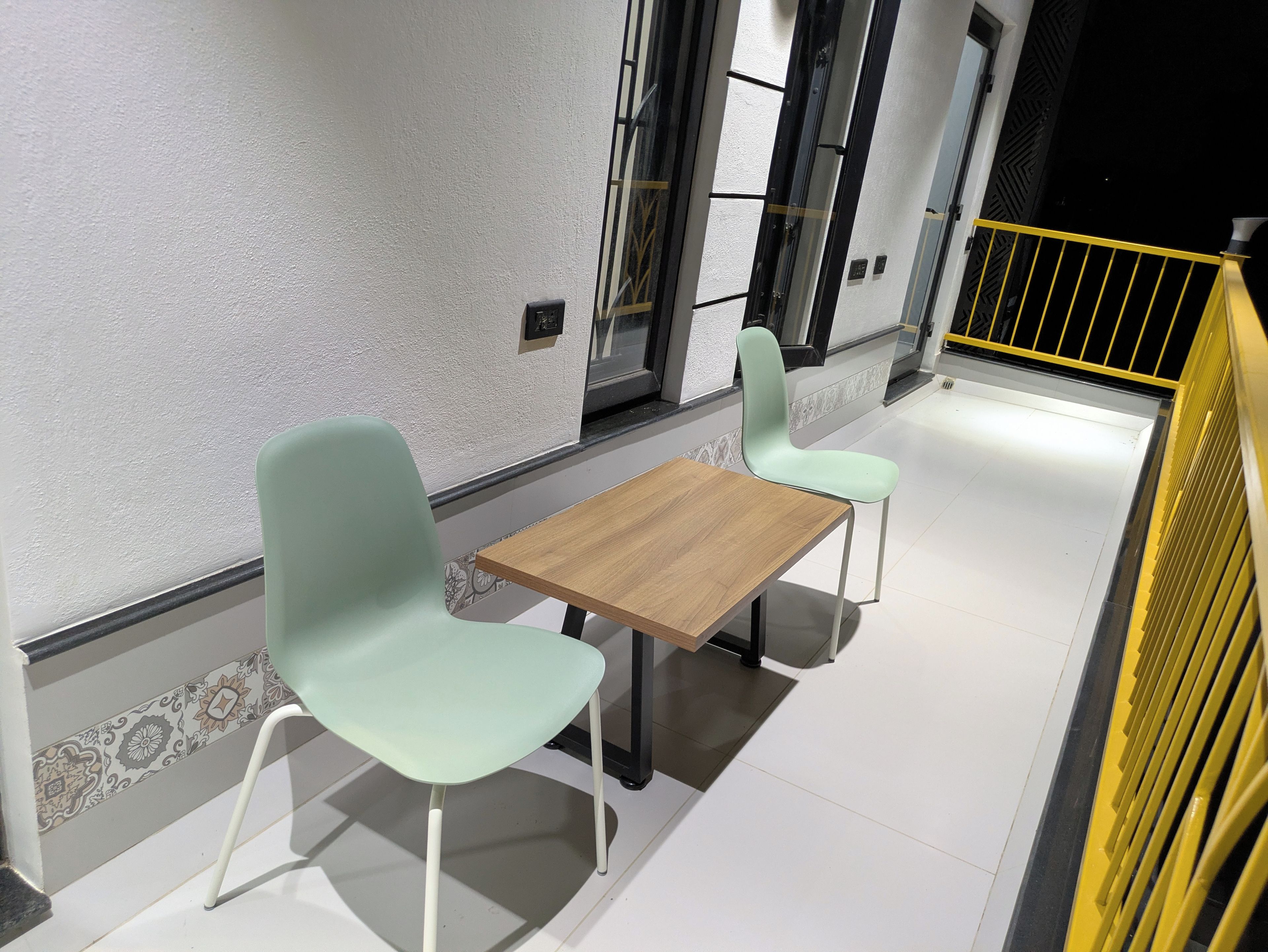 A clean, modern interior with two light-colored chairs and a wooden table, suggesting a casual dining area.