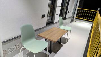 A clean, modern interior with two light-colored chairs and a wooden table, suggesting a casual dining area.