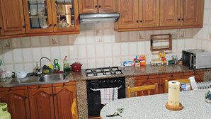 A kitchen with wooden cabinets, a gas stove, a microwave, and a dining table with chairs. - Holiday Home 'Beiramar' with Private Terrace and Wi-Fi (Boiro)