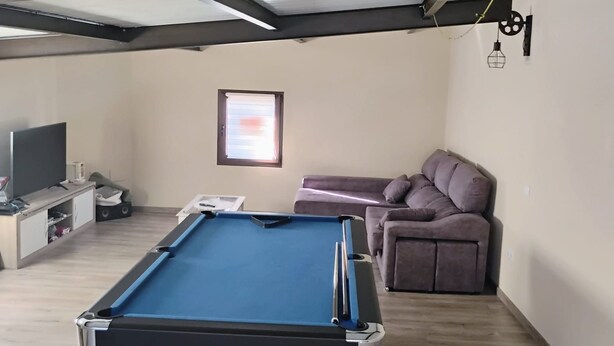 A room with a pool table, a sofa, a television, and a window. - Holiday Home 'Beiramar' with Private Terrace and Wi-Fi (Boiro)