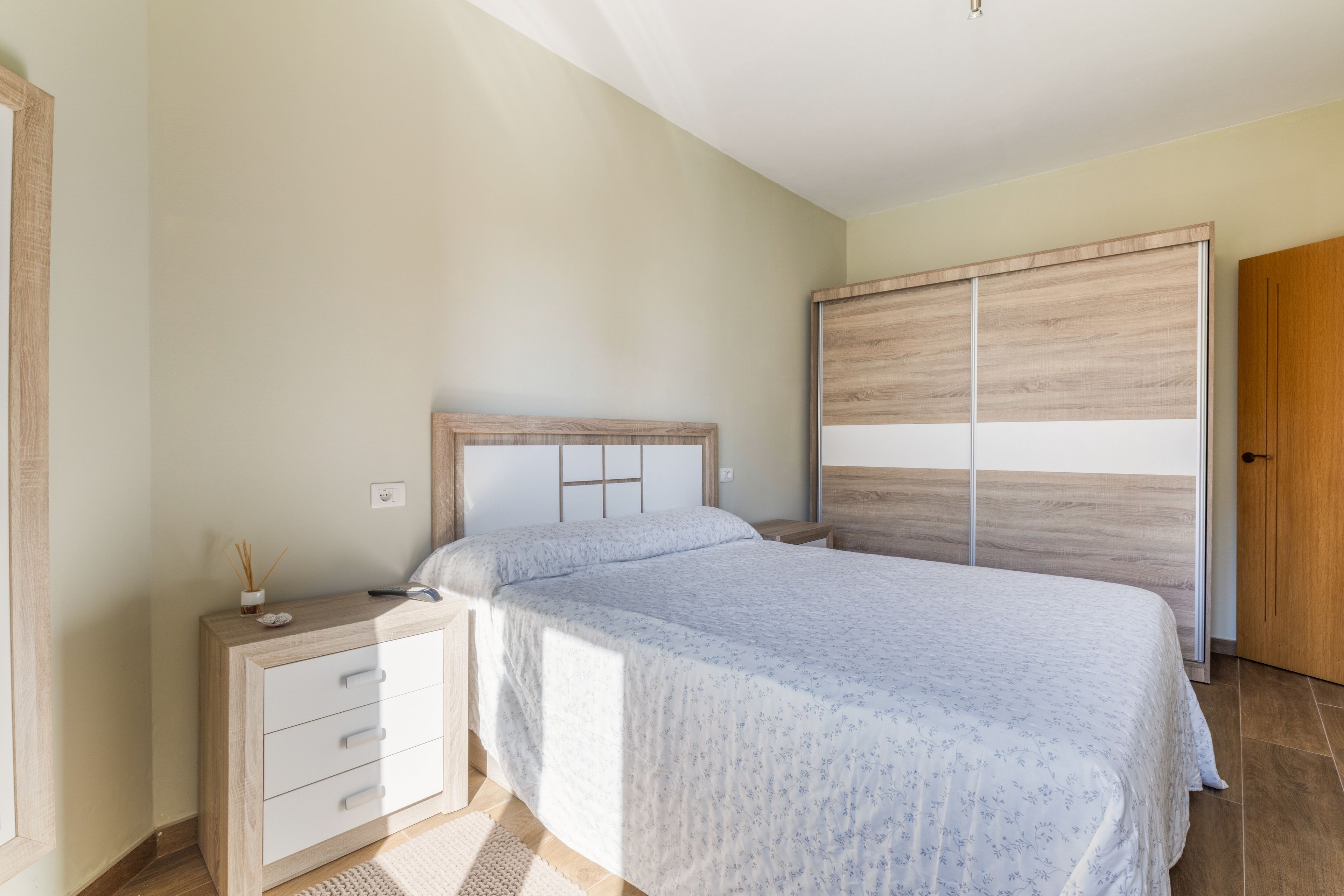 Una camera da letto con un letto, un comodino, una cassettiera e un armadio.