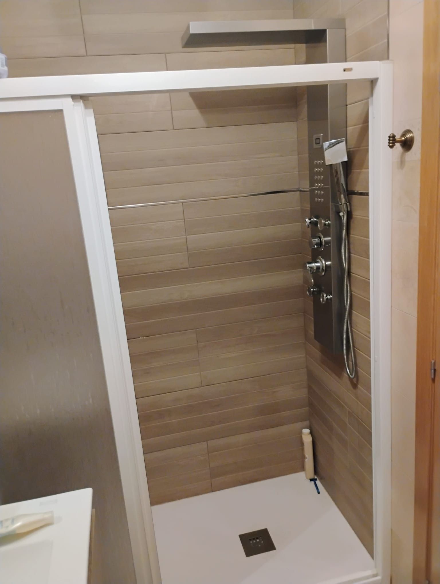 Een douche met bedieningspaneel, douchekop en afvoer.