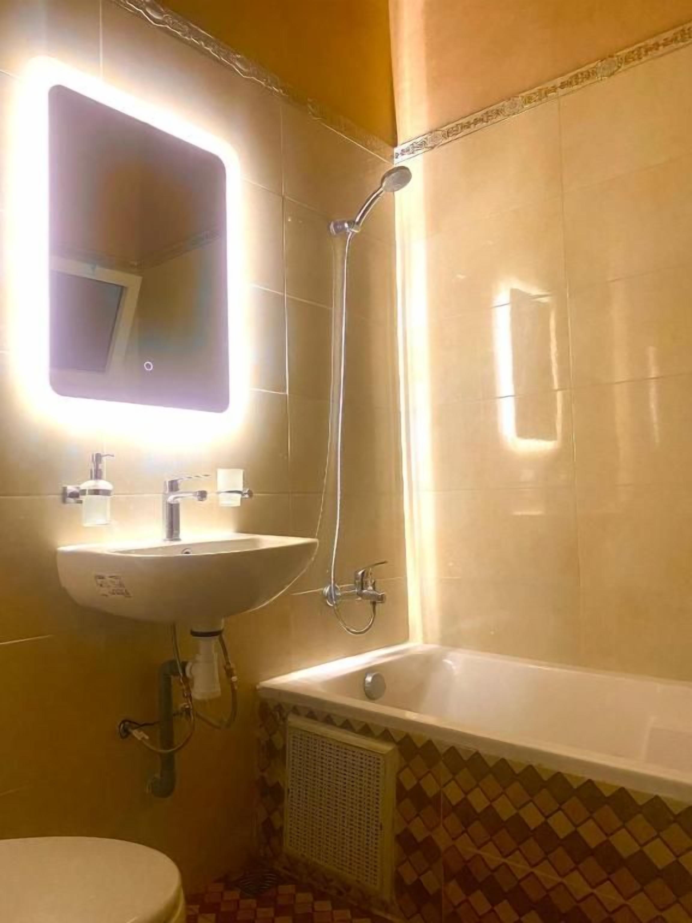 A bathroom with a sink, mirror, shower, and toilet.