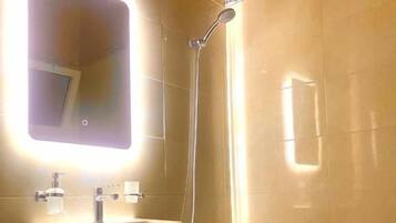 A bathroom with a sink, mirror, shower, and toilet.