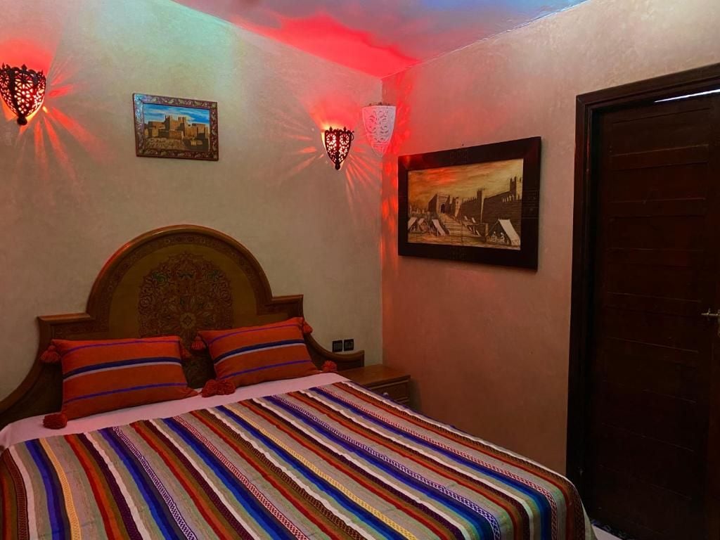 Una camera da letto con un letto, una testiera, due lampade a parete e due quadri incorniciati.