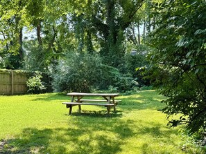 A picnic table in a grassy backyard with trees and a wooden fence. - Comfy and cozy East Nashville cottage! (Nashville)