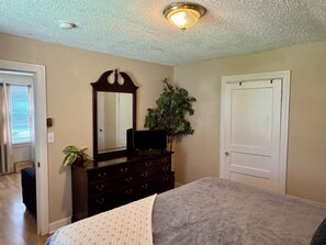 A bedroom with a bed, dresser, mirror, and a door. - Comfy and cozy East Nashville cottage! (Nashville)