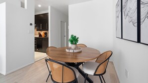 A dining area with a round table, wicker chairs, and a potted plant. - Stylish 850 SF SoHo 1BR W/D (New York)