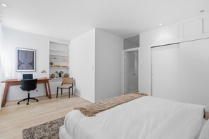 Une chambre à coucher comprenant un lit, un bureau avec une chaise, une bibliothèque et une armoire.