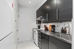 Una cuina moderna amb armaris foscos, un rentapeus d'acer inoxidable i forn encastrat.