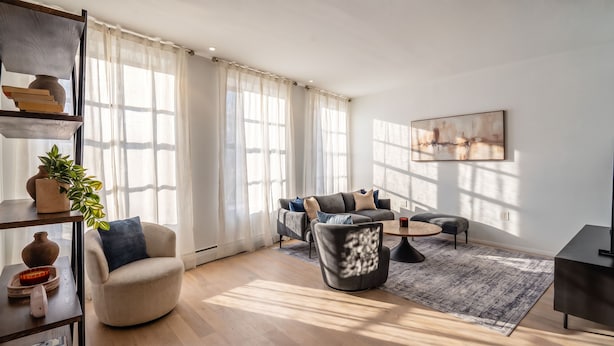 A modern living room with a sofa, armchair, coffee table, and a television. - Stylish 850 SF SoHo 1BR W/D (New York)