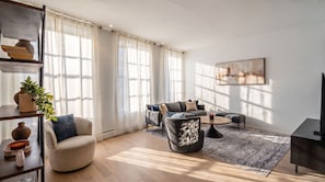 A modern living room with a sofa, armchair, coffee table, and a television.