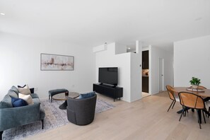 A modern living room with a grey sofa, a round coffee table, and a flat-screen TV.