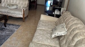 Ein Wohnzimmer mit zwei Sofas, einem Esstisch und einer dahinterliegenden Küche.