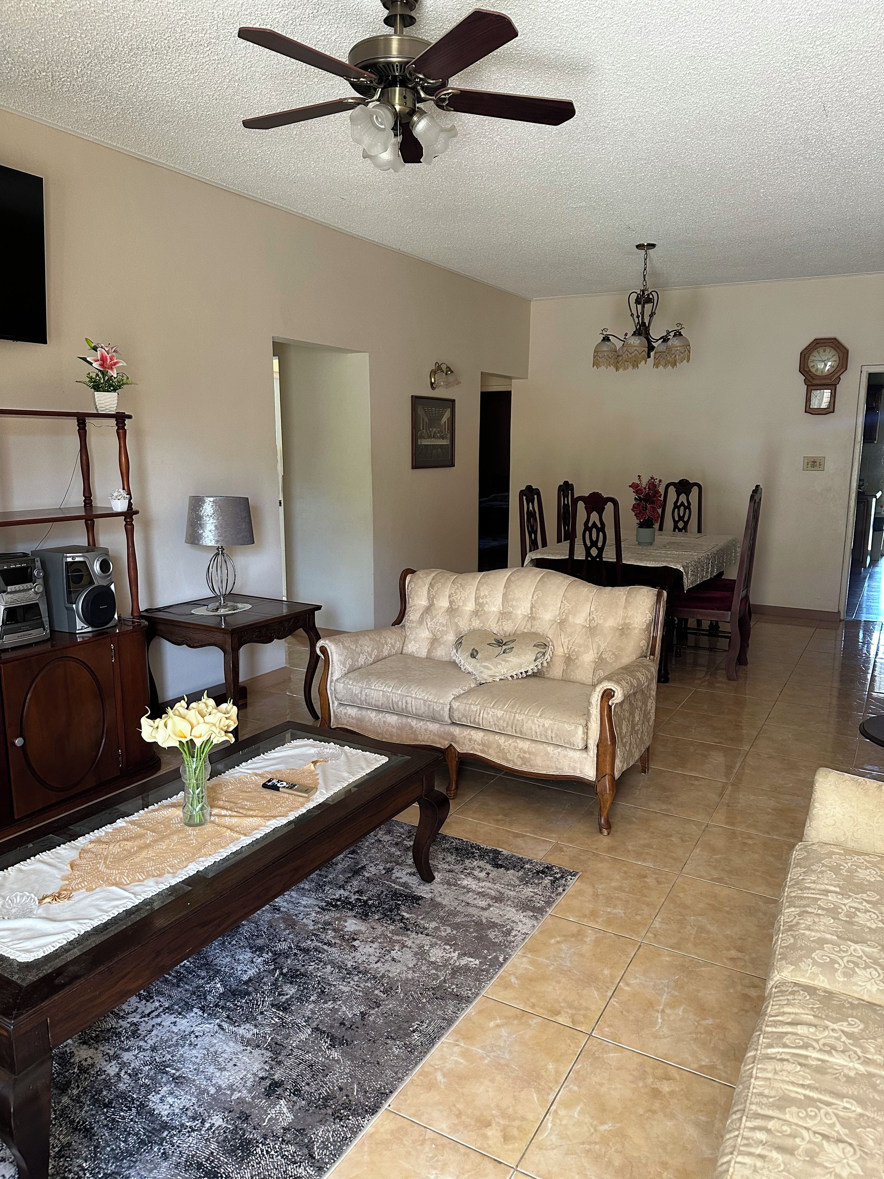 A living room with a sofa, coffee table, and a ceiling fan.