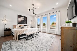 A bedroom with a bed, bedside tables, a large window, and a view of the outdoors. - East Nashville game room house walkable to Hattie B's, sleeps 12 on VRBO (Nashville)