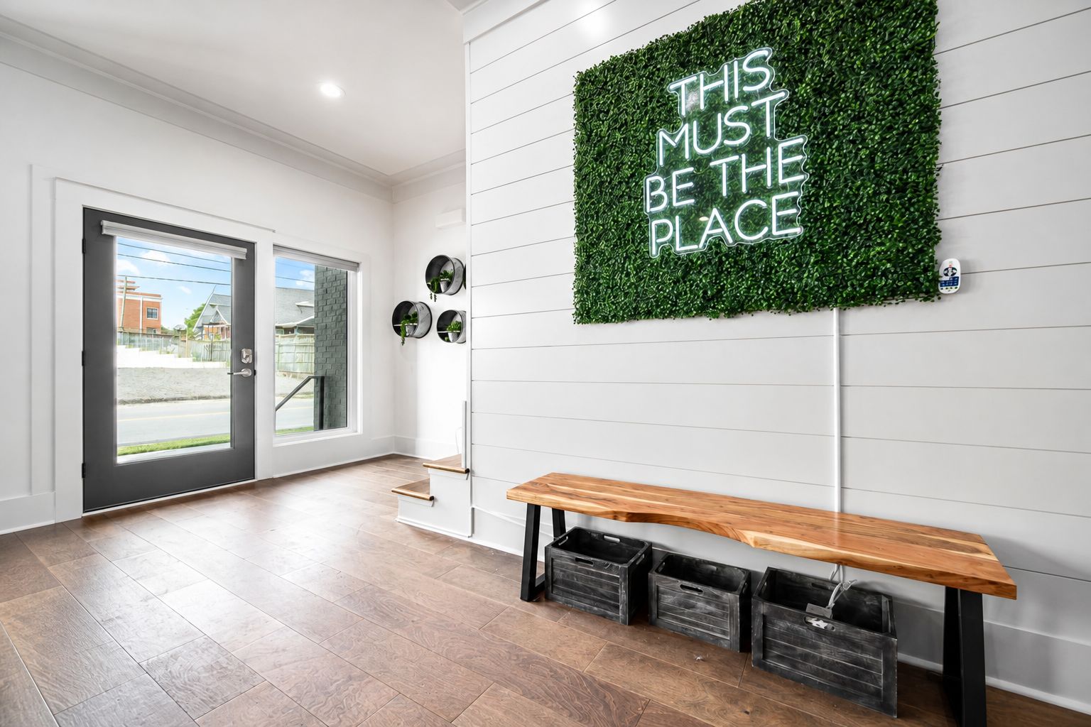 A modern interior with a bench, a wall-mounted sign, and a door leading outside.