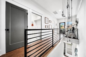 A modern interior with a black metal railing, white walls, and a wooden floor. - East Nashville game room house sleeps 12, across from Hattie B's (Nashville)