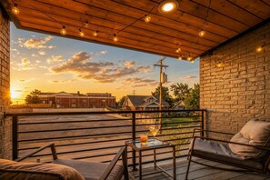 A balcony with a view of a sunset, a brick wall, and a wooden ceiling. - East Nashville game room house sleeps 12, across from Hattie B's (Nashville)