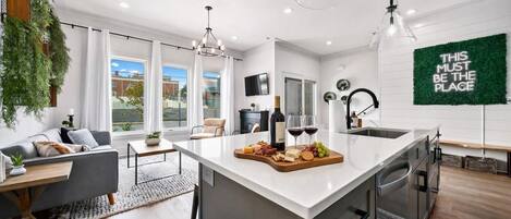Una cocina moderna con una isla central, comedor y vistas al exterior.