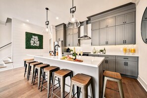 A modern kitchen with a bar area, grey cabinets, and a green wall decoration. - East Nashville game room house walkable to Hattie B's, sleeps 12 on VRBO (Nashville)