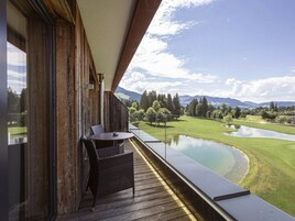 A balcony with a view of a golf course and a pond.