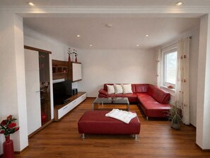 A modern living room with a sectional sofa, a flat-screen TV, and a glass coffee table. - Holiday Apartment With 3 Bedrooms (Norderney)
