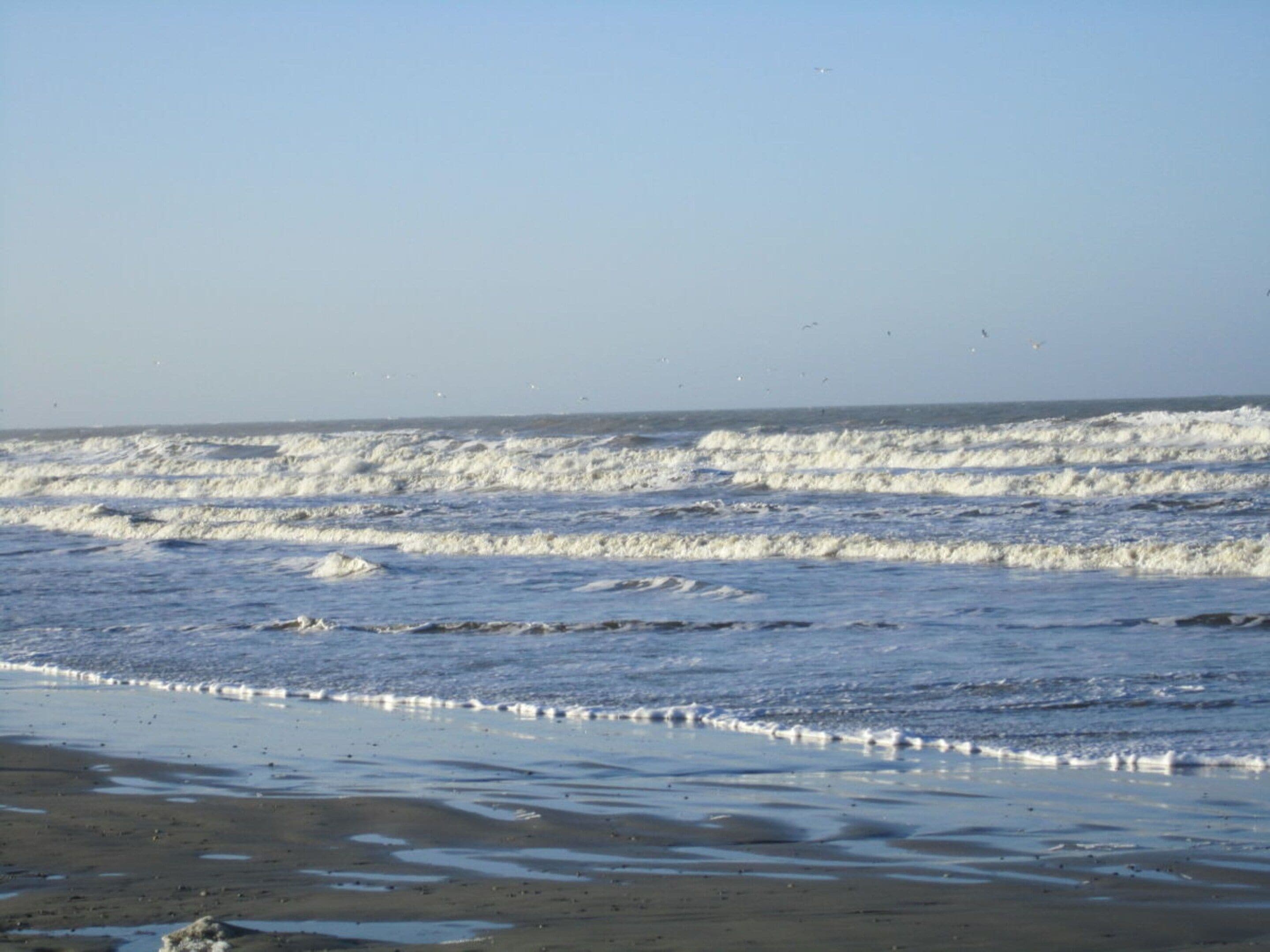 A beach with waves and a clear sky.