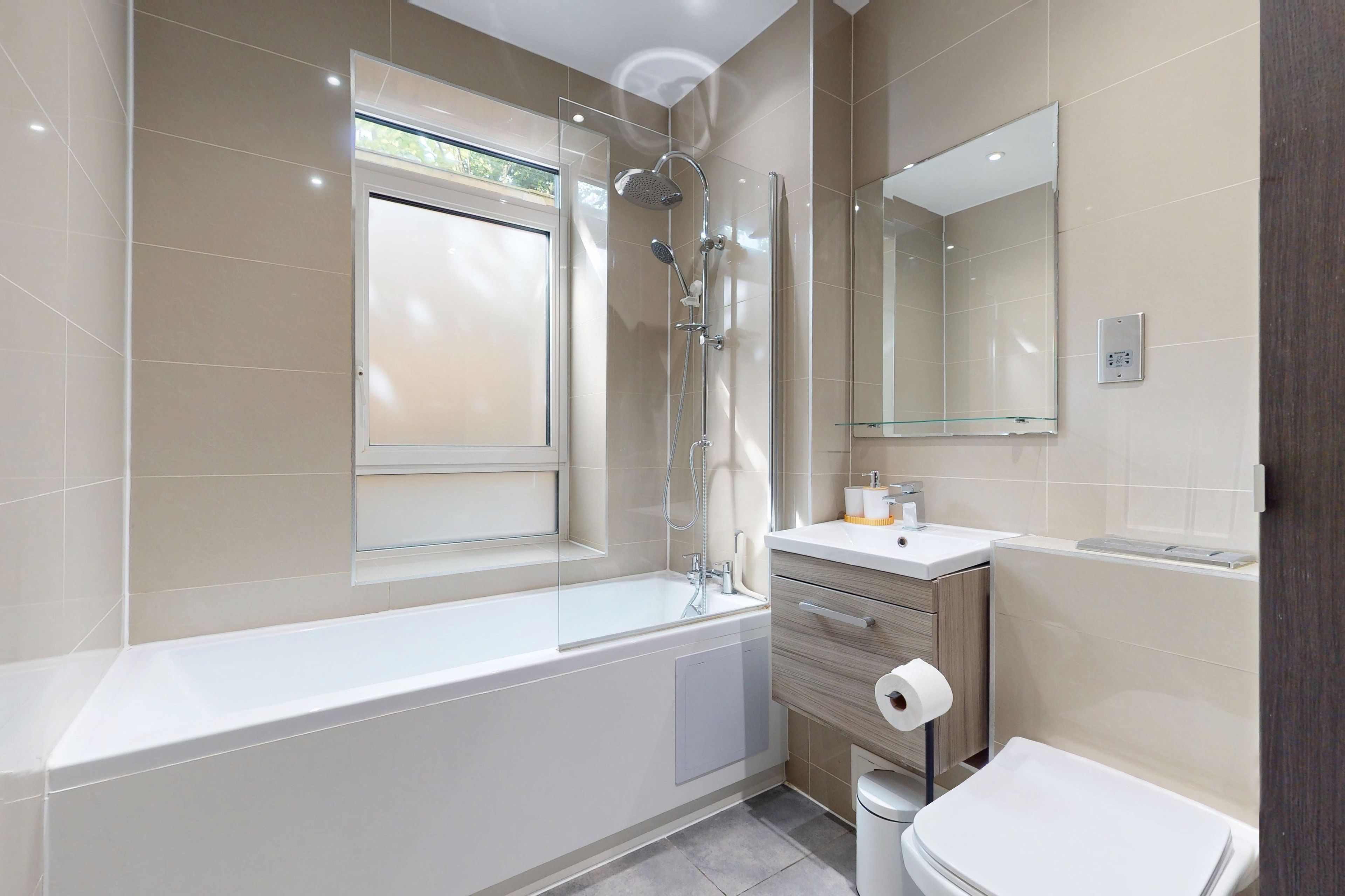 Ein modernes Badezimmer mit einer Badewanne, einer Dusche, einer Toilette und einem Waschbecken.
