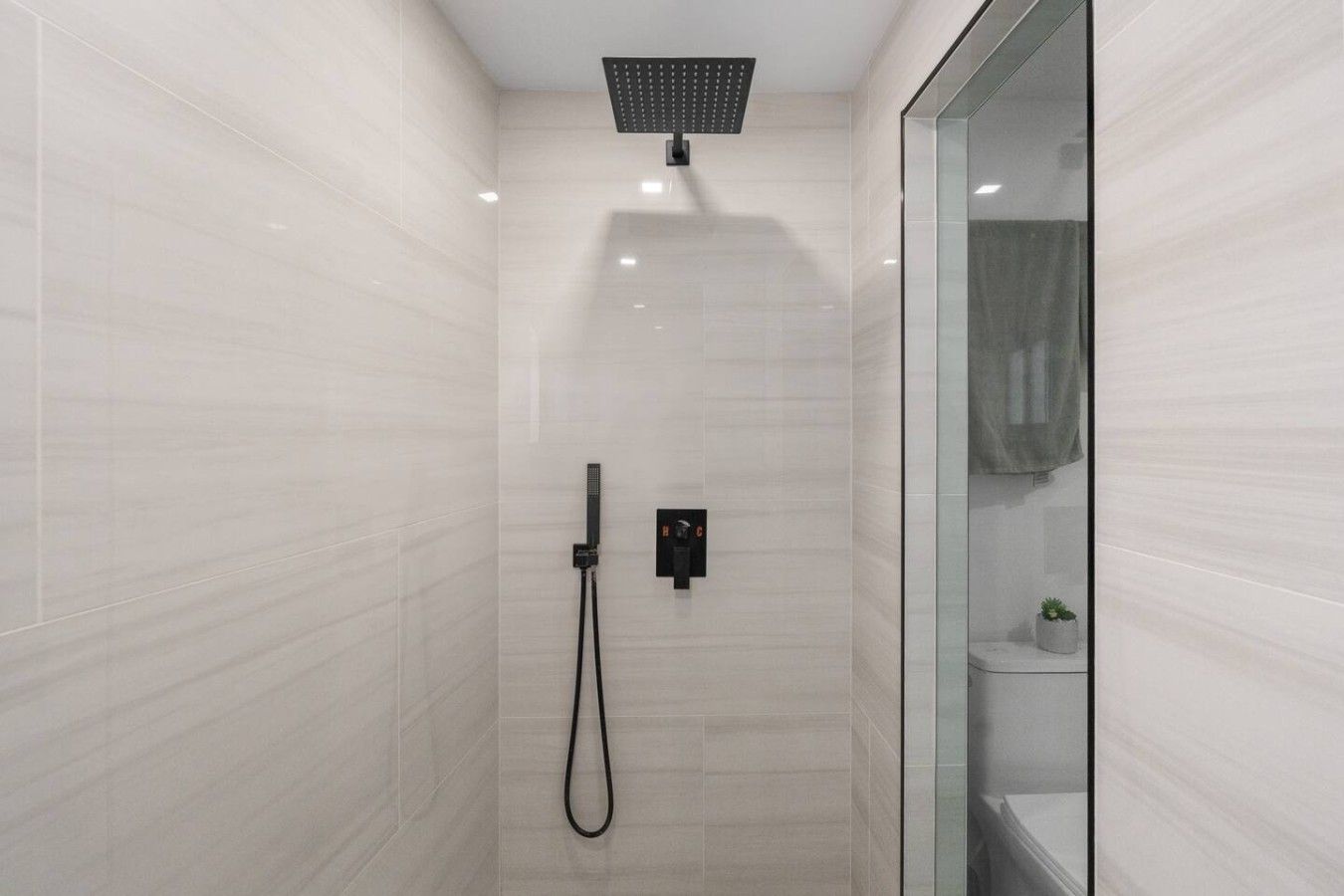 A modern shower with a handheld showerhead and a wall-mounted control panel.