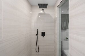 Ducha moderna con cabezal de ducha manual y panel de control en la pared.