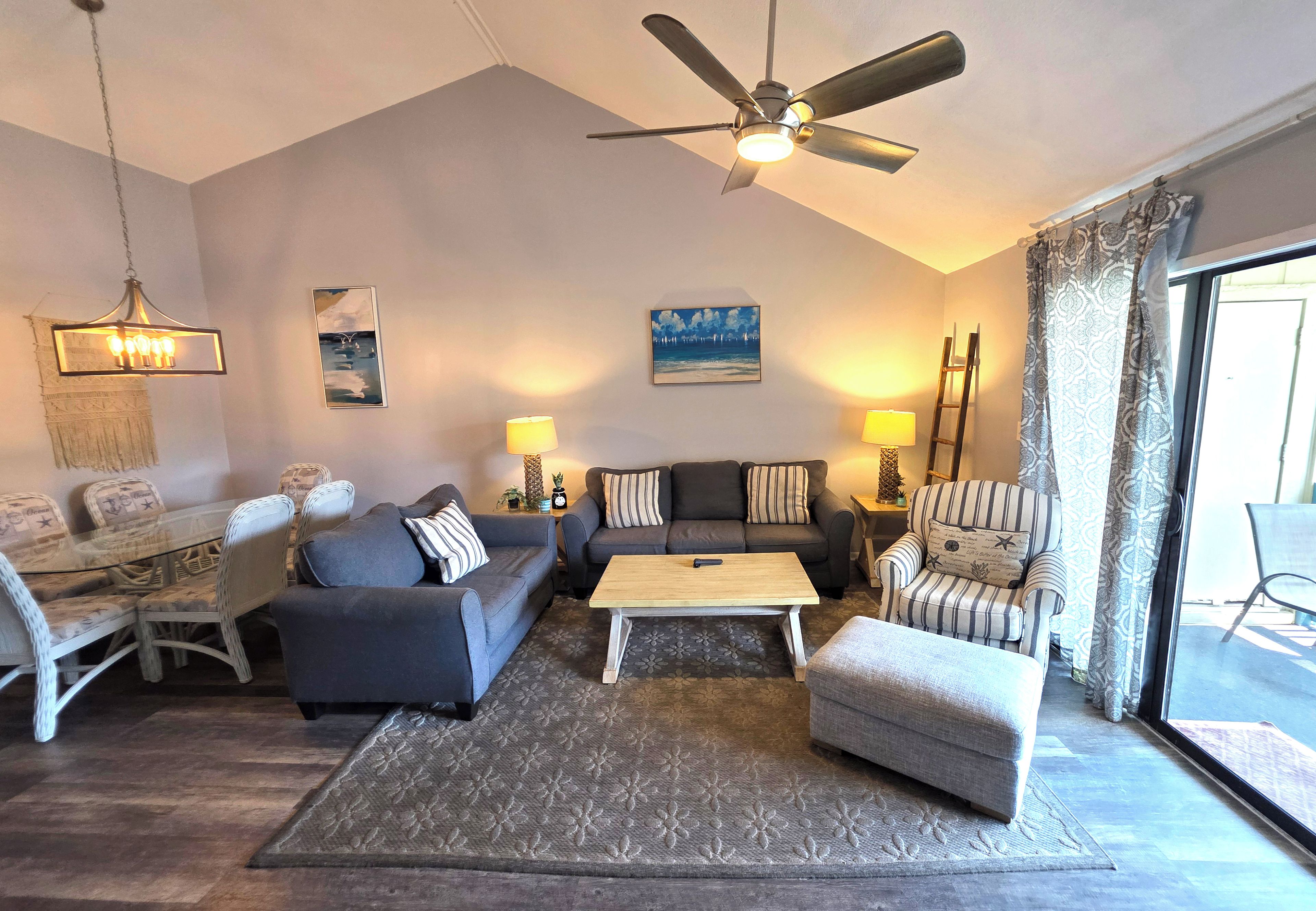 A living room with a ceiling fan, a sofa set, a coffee table, and a patterned rug.
