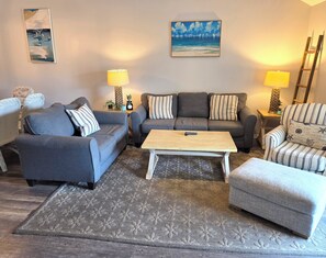 Ein Wohnzimmer mit zwei Sofas, einem Couchtisch und einem gemusterten Teppich.
