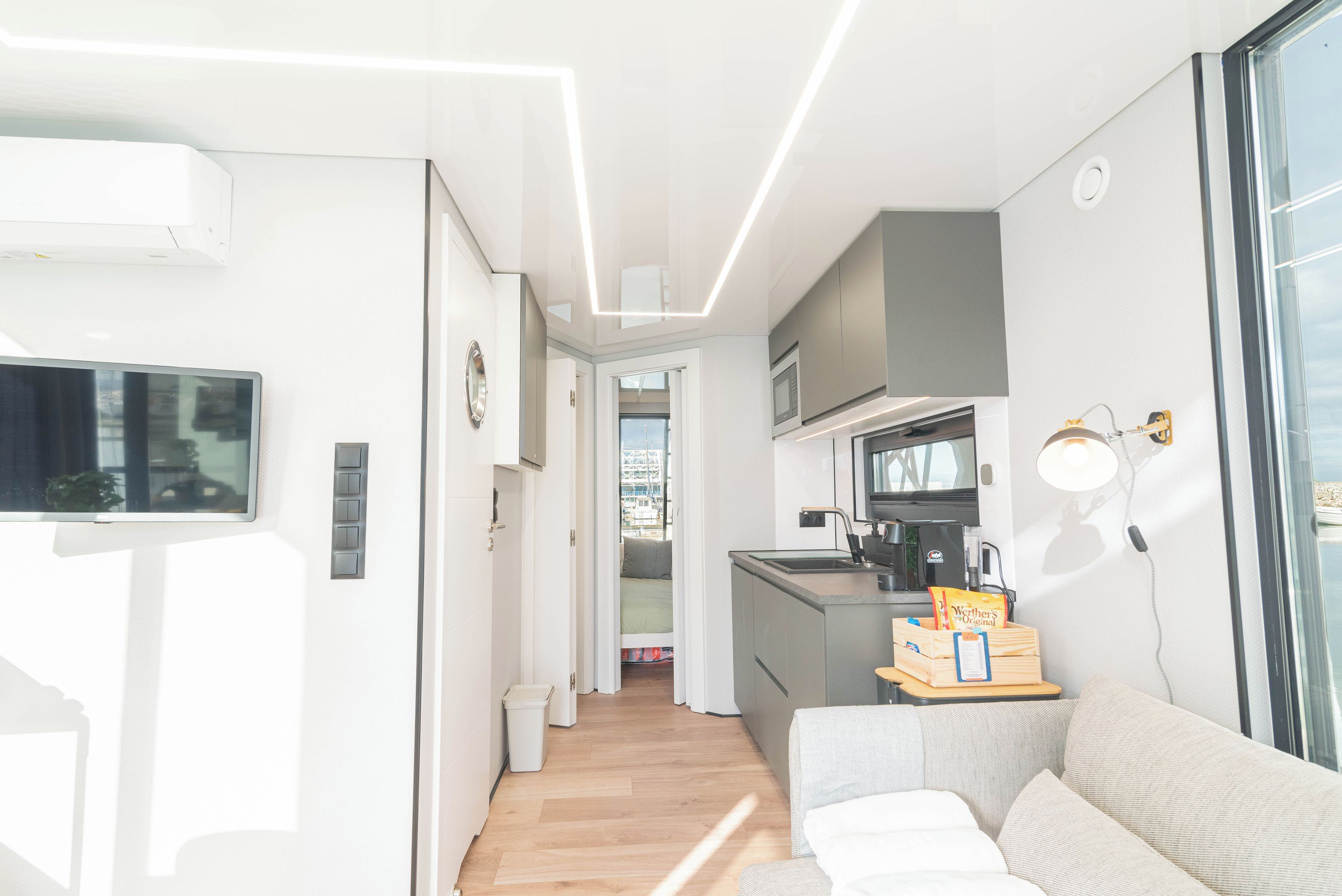 Un espace de vie compact comprenant un coin cuisine, un canapé, une télévision et une fenêtre.