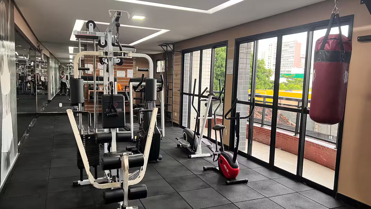 A gym with various exercise equipment, large windows, and a punching bag.
