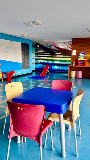 A children's play area with a blue floor, a red slide, and colorful chairs. - 1904 Nazaré · 2-bedroom apartment with garage in the neighborhood of (Belém)