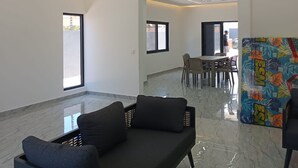 Interior moderno com sofá, parede estampada e área de refeições.