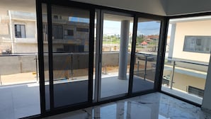 Quarto espaçoso com grande porta de vidro deslizante que dá para uma varanda externa.