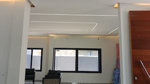 Quarto amplo com piso de mármore polido, escada de madeira e uma grande janela com vista para um edifício.
