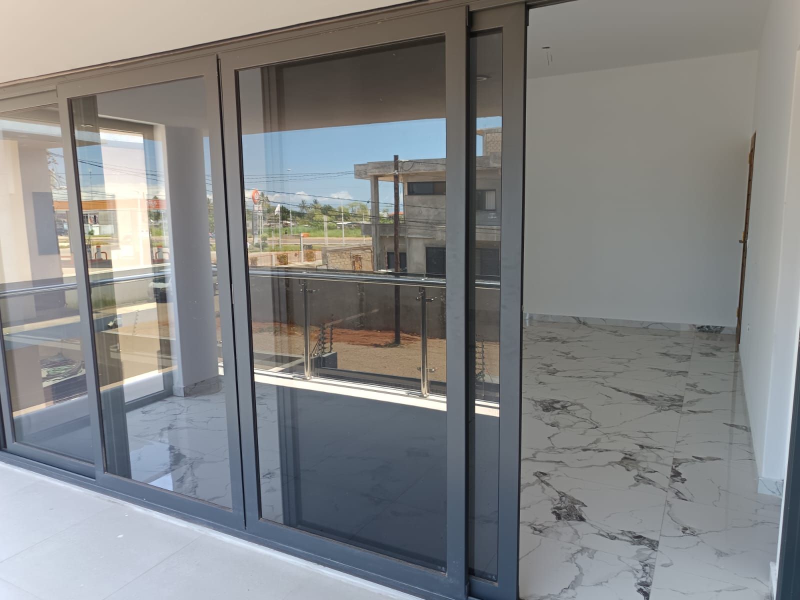 Ein modernes Gebäude mit einer Glastür, die auf einen Balkon mit Metallgeländer führt.